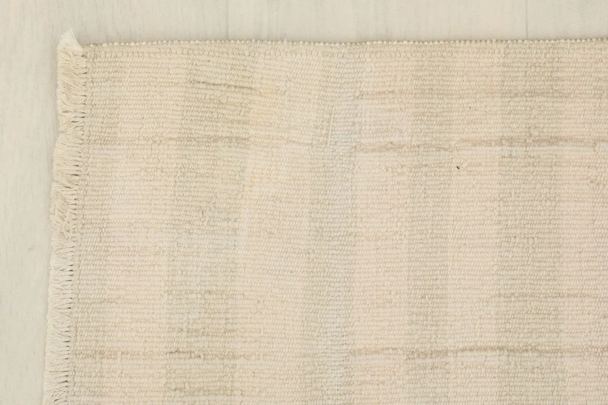 Corner detail of the rug, showing the finished edge and short fringe.