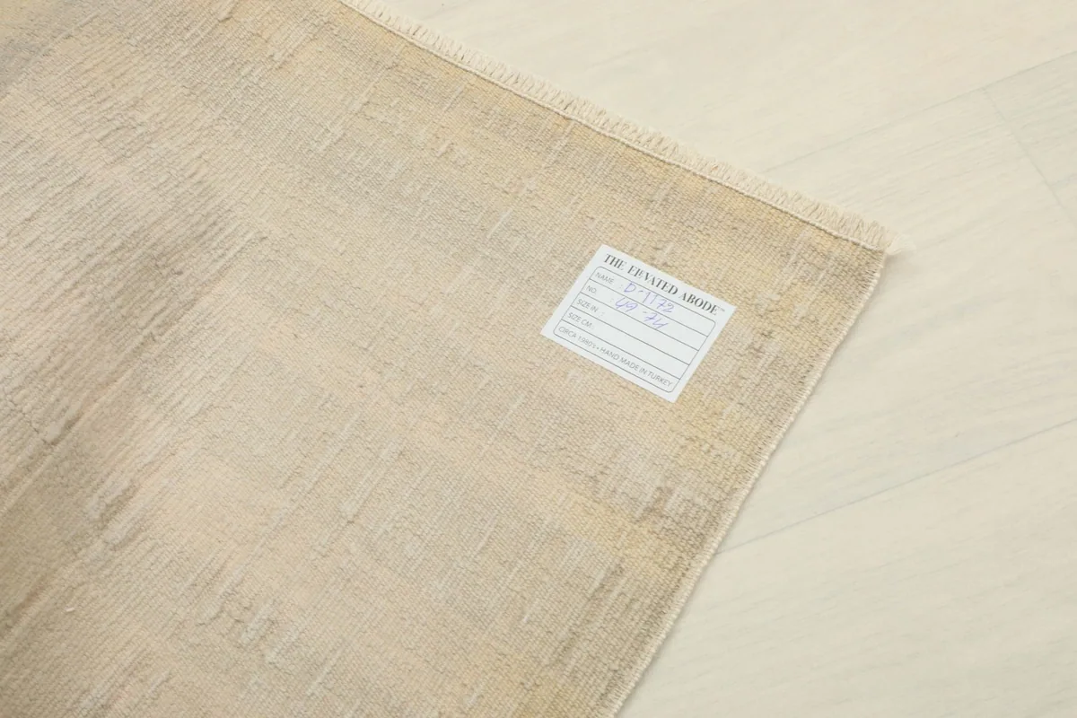 View of the back of the rug with a label, showcasing the cotton foundation and knotting.