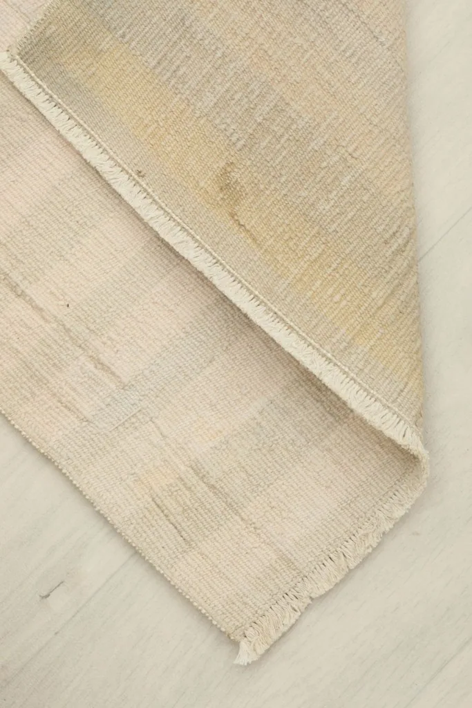 Partial fold of the rug, revealing the back of the cotton foundation and its construction.