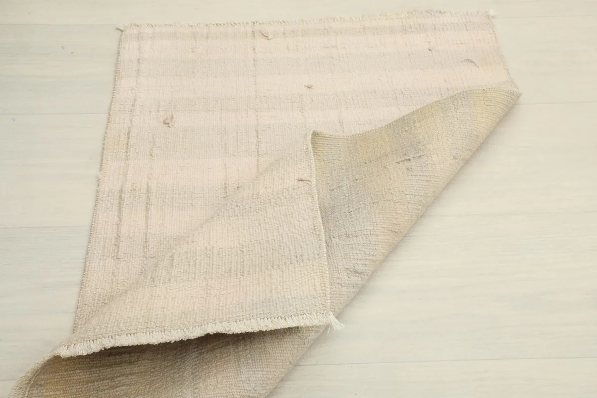 Rug partially folded, showing the flexibility and the reverse side of the hand-knotted construction.