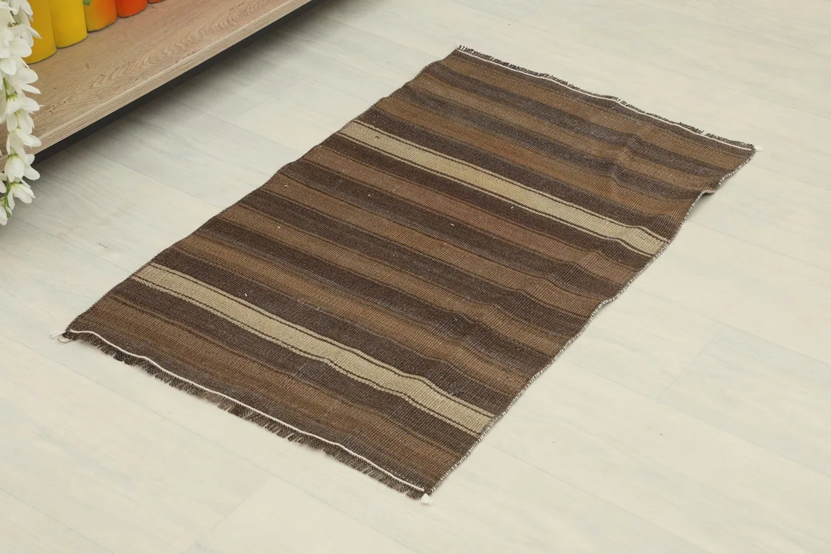 Angled view of the hand-knotted wool rug with earthy brown and tan stripes on a white floor