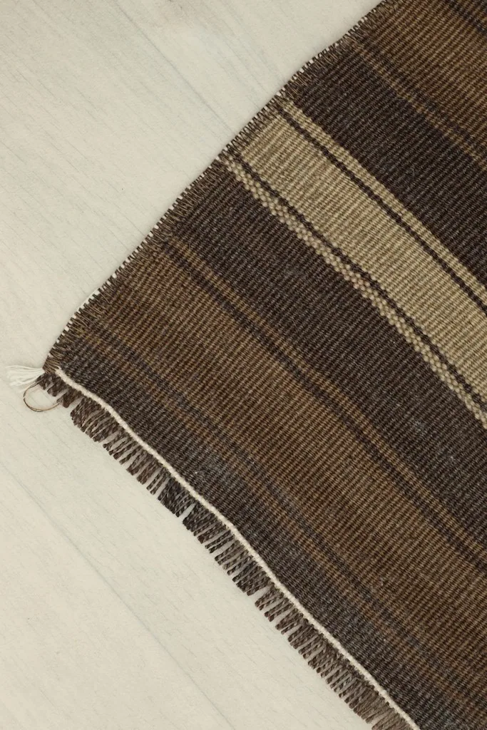 Corner view of the rug, showcasing the subtle patina and the intricate weaving