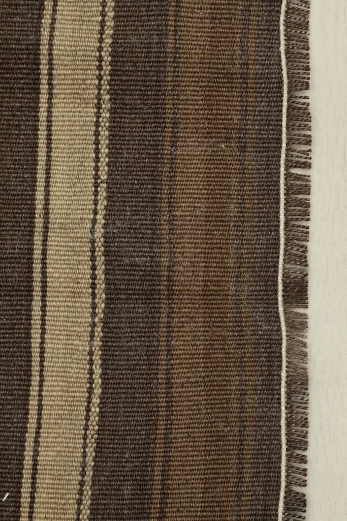 Close-up detail of the striped pattern and fringe on the vintage Anatolian doormat