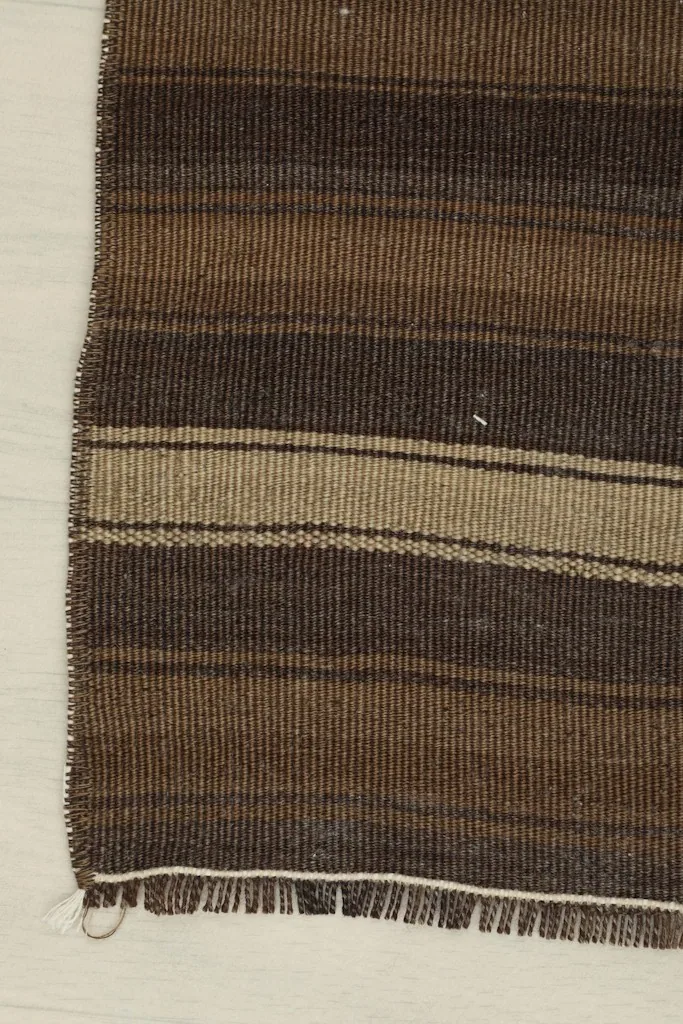 Side view showing the finished edge and fringe of the brown and tan vintage doormat