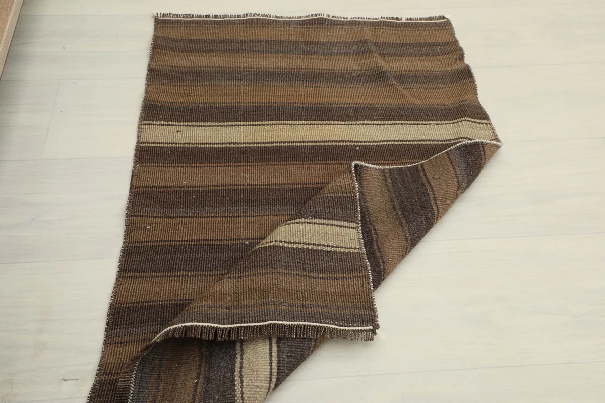 The striped rug partially folded, demonstrating its pliable nature and construction