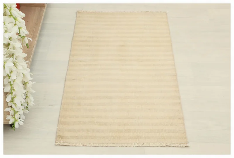 Full overhead view of the beige and tan striped vintage Anatolian wool doormat on a white background.