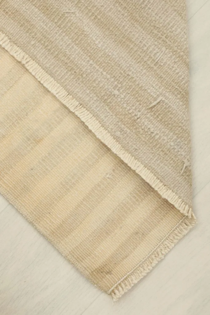 Folded corner revealing the back of the hand-knotted rug, showing the cotton foundation and construction.