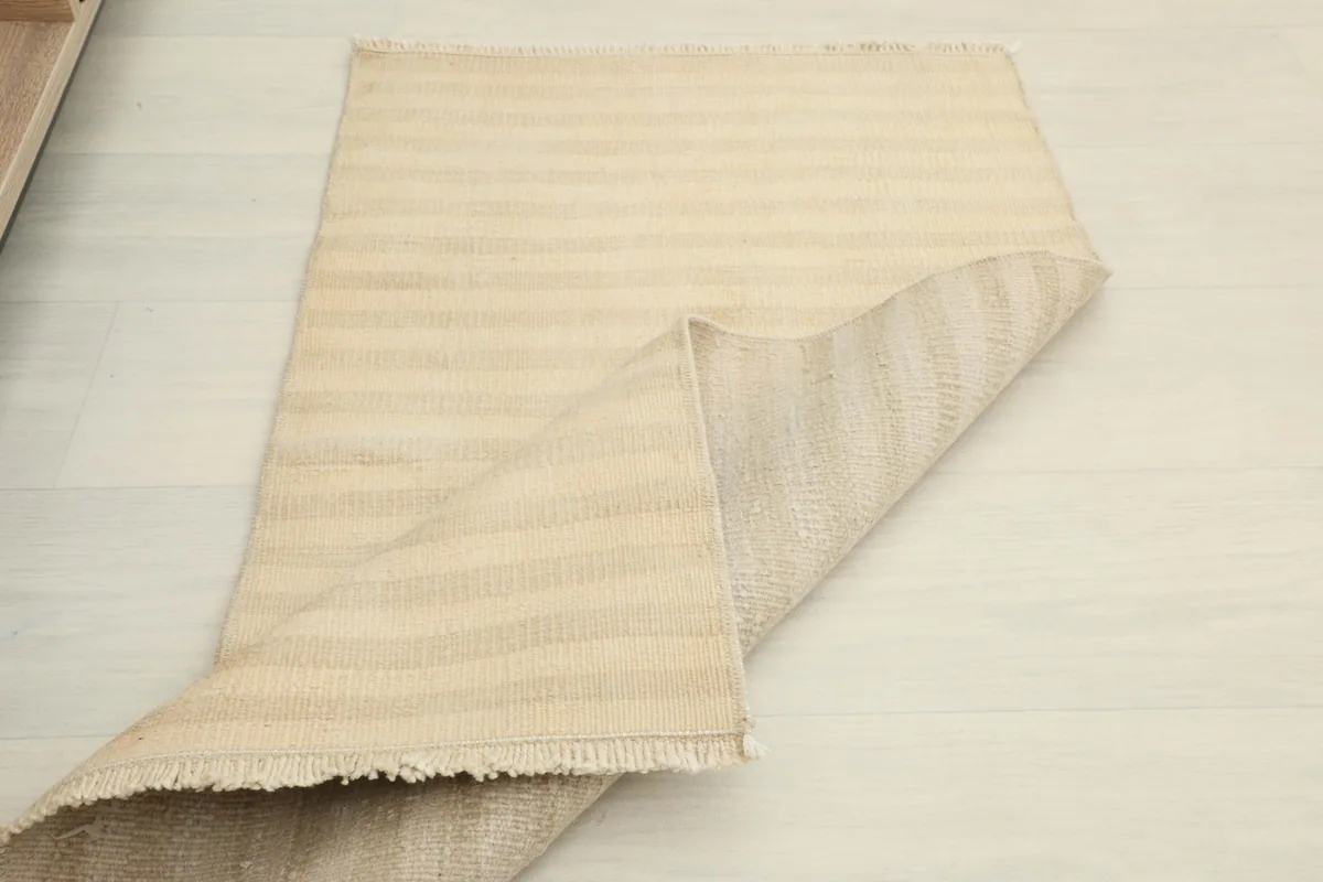 Rug partially folded, displaying both the pile side and the back of the hand-knotted construction.