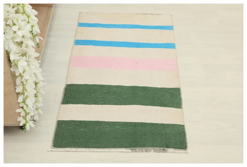 Full top view of the cream, green, pink, and blue striped vintage Anatolian rug on a white background.