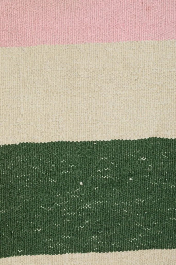 Detailed shot of the wool pile, showcasing the hand-knotted texture and color variations within the stripes.
