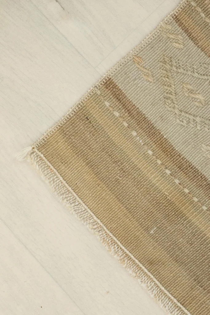 Corner view of the runner rug, highlighting the fringe and natural wear.