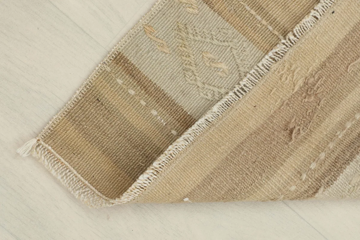 View of the rug folded to show the cotton foundation and reverse side.