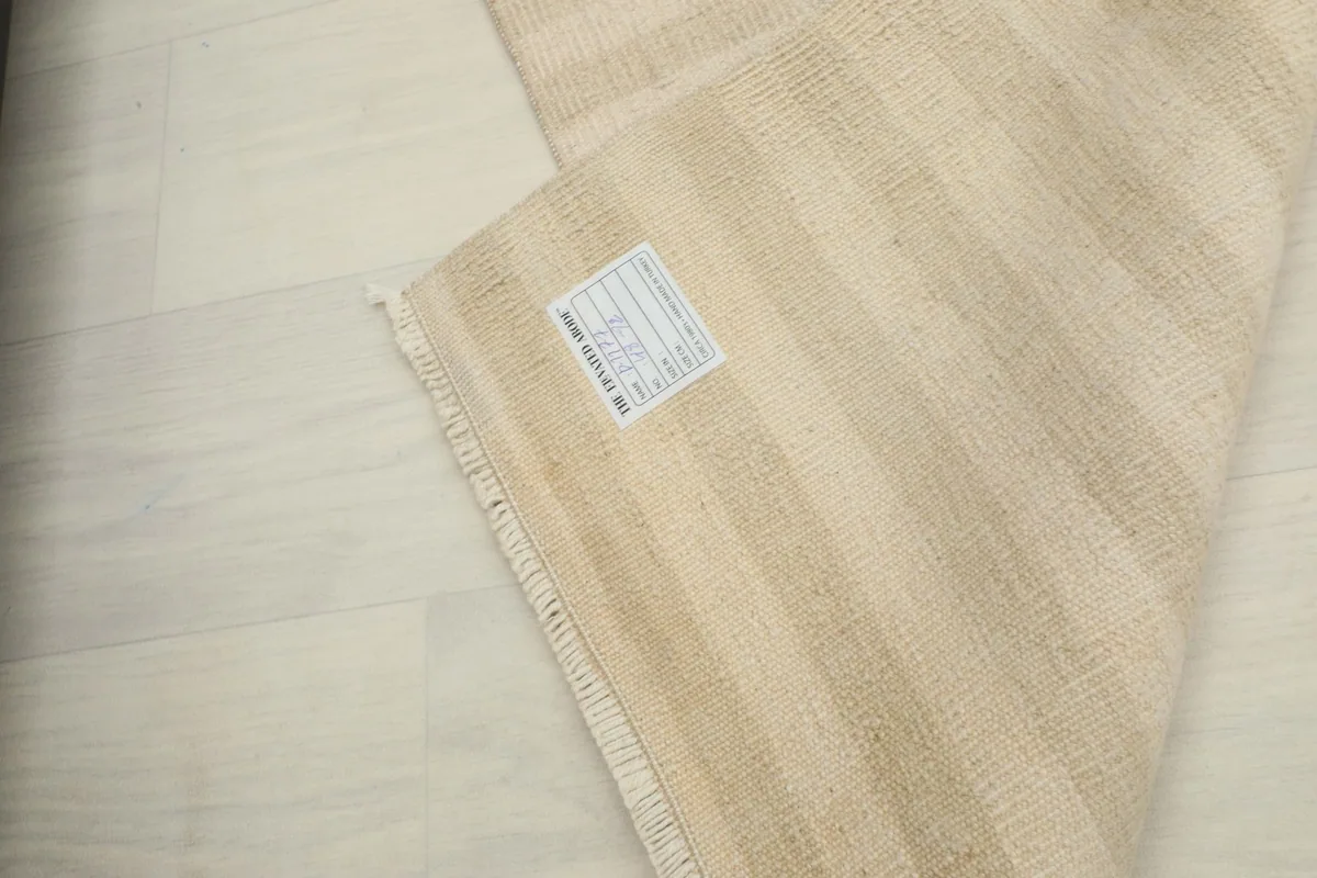 View of the back of the hand-knotted rug, showing the cotton foundation and a label.