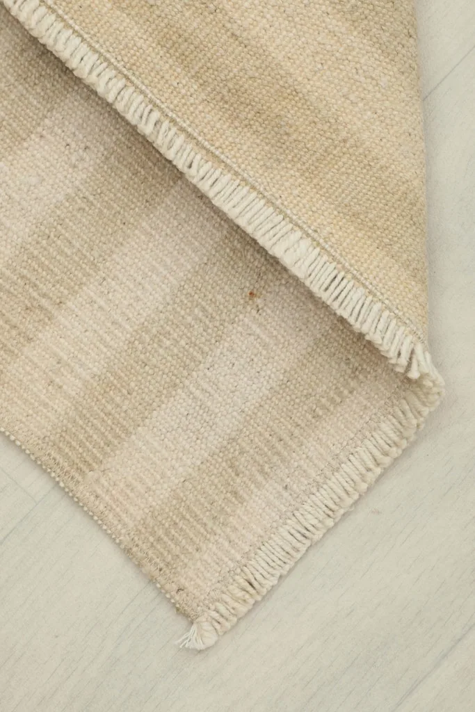Rug folded to show the back and front texture, highlighting the beige stripes.