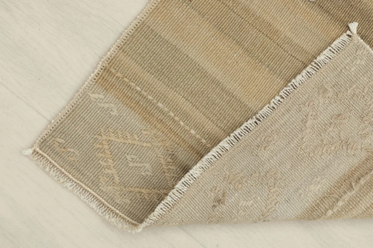 View of the back of the rug and a folded corner, showing the cotton foundation
