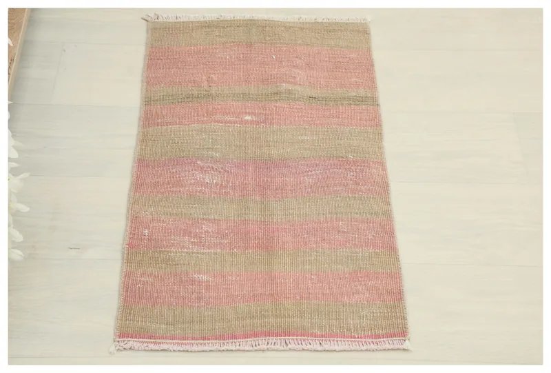 Full top view of the 1'3" x 2'4" pink and beige striped vintage Anatolian rug on a white background.