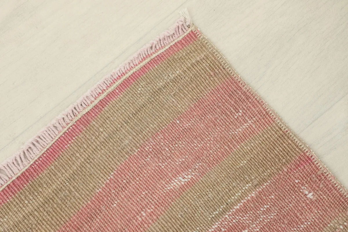 Corner view of the rug, showing the straight edge and the hand-finished fringe.