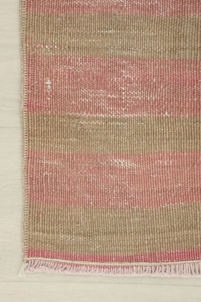 Detailed view of the rug's edge, focusing on the consistent striped design and fringed end.