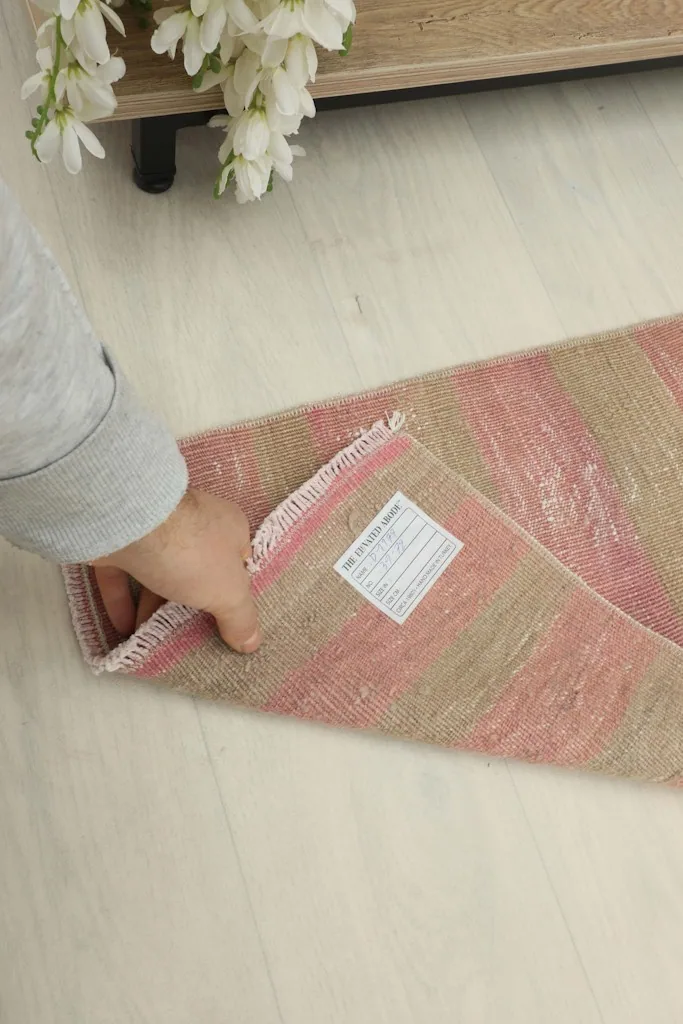 Hand holding a corner of the rug, displaying the back of the rug and the woven label.
