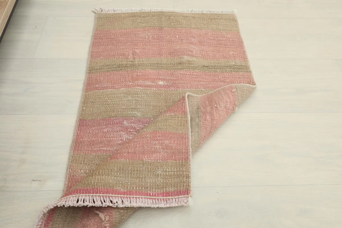 Partially folded rug on a white floor, illustrating its flexibility and compact size.