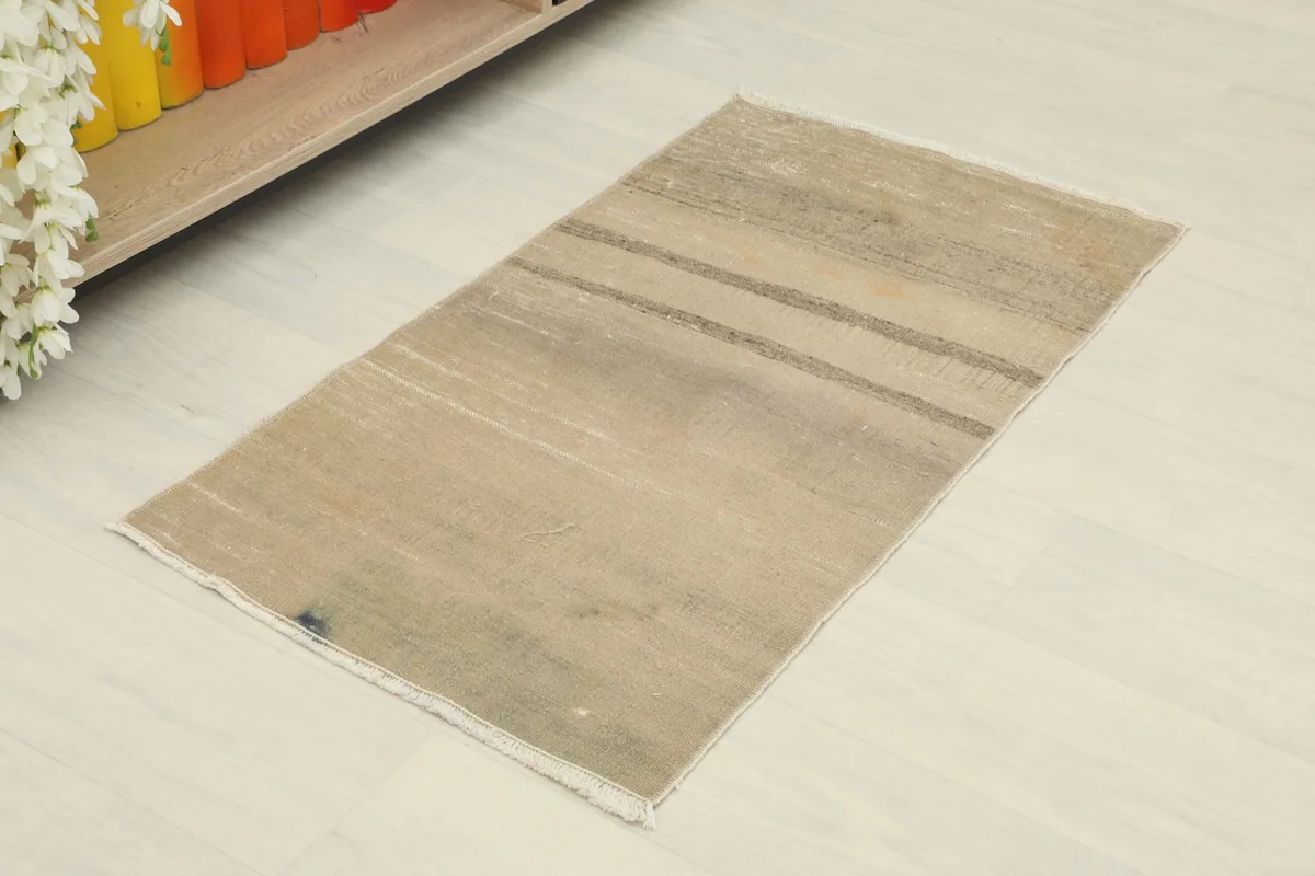 Angled overhead view showcasing the tan color and subtle gray stripes of the hand-knotted rug