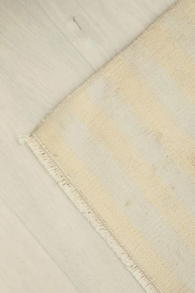 Corner view of the rug, highlighting the texture of the wool pile and the subtle color variations.