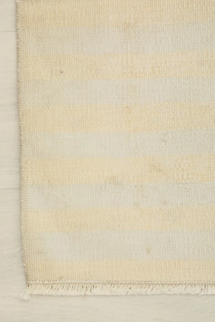 Detail showing the subtle striped pattern and the finished edge of the hand-knotted vintage rug.