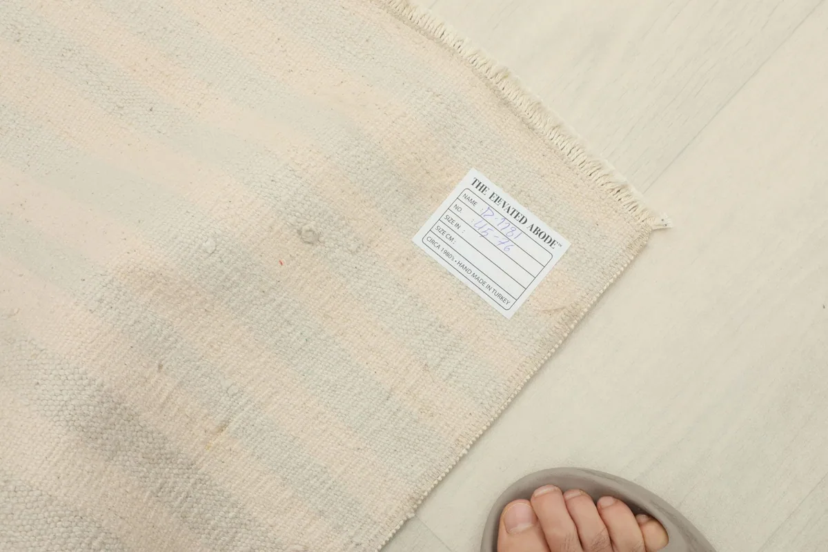 Detail of the rug's label on the back, with a foot for scale, indicating its vintage origin.