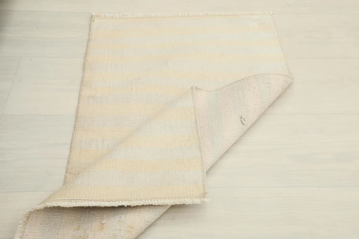 The rug partially folded to show both the front pile and the sturdy cotton foundation.