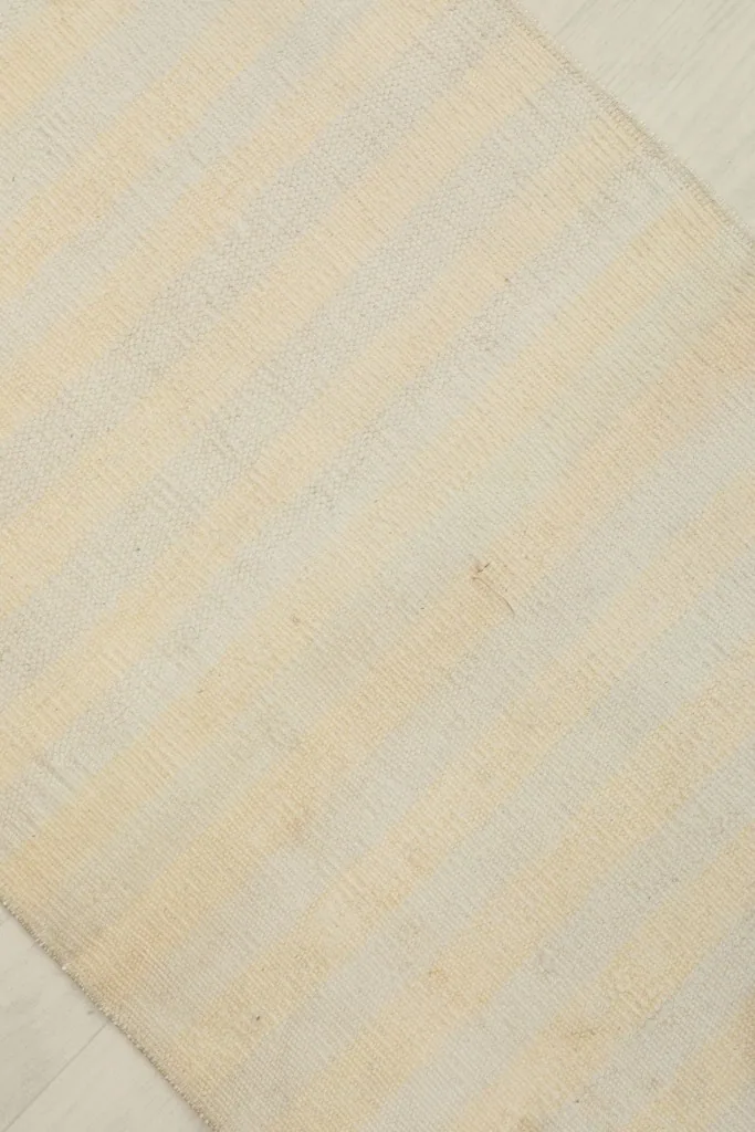 Overhead view focusing on the central area of the rug, displaying the ivory and beige striped pattern.