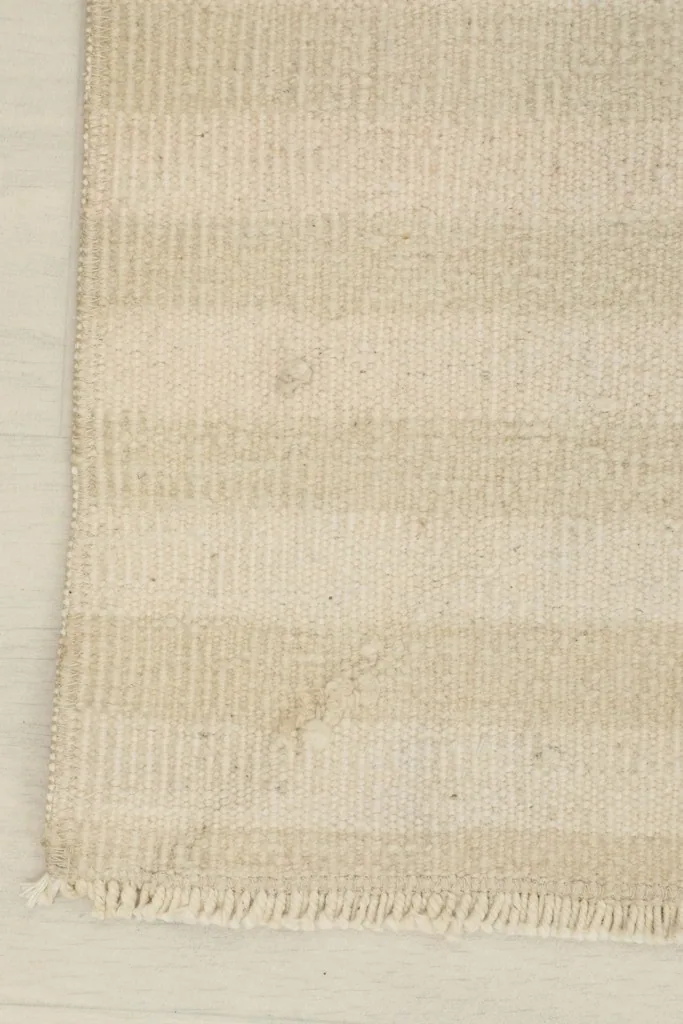 Close-up of the rug's corner, showing the striped pattern and the short fringe.