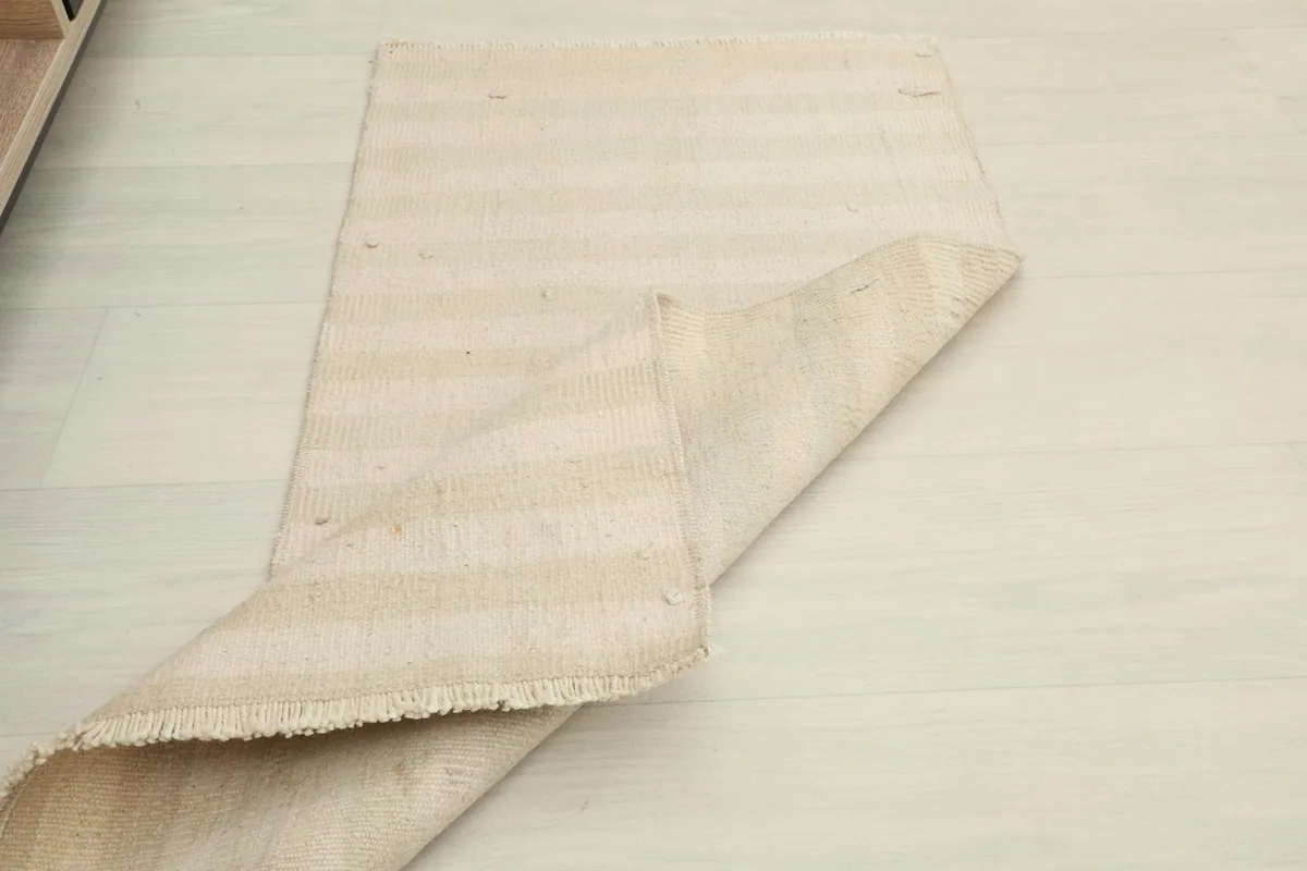 Rug partially unfolded on the floor, demonstrating its size and subtle color variations.