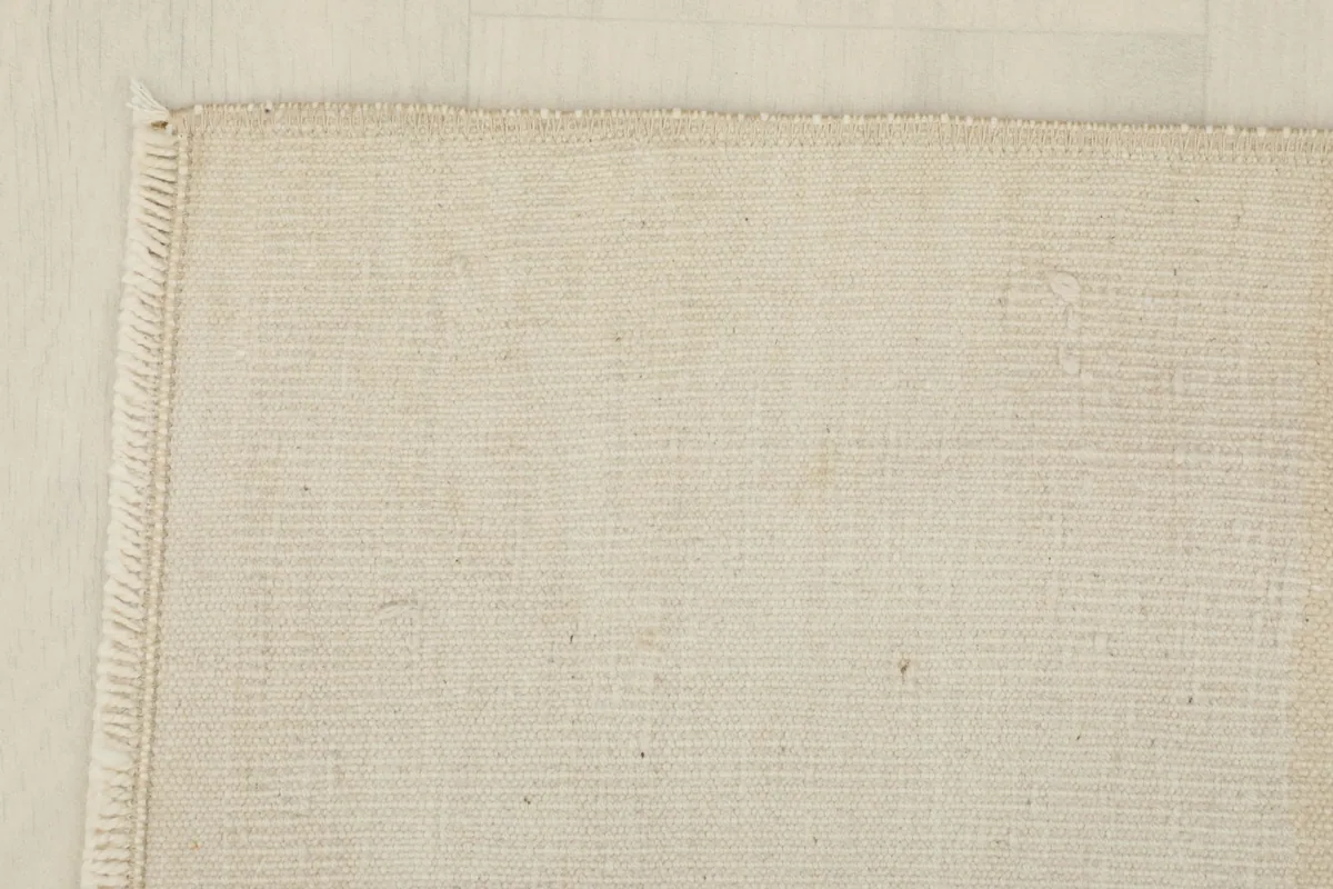 Corner detail of the rug, revealing the neat edge finishing and short fringe