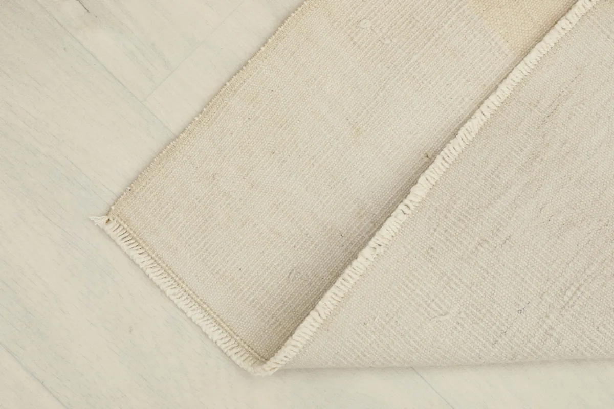 View of the rug partially folded, showing the cotton foundation and flexibility