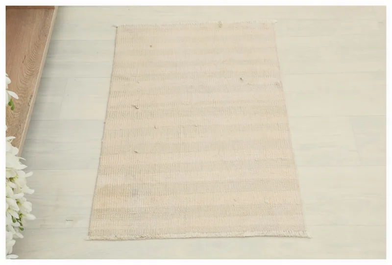 Top view of the 1'7" x 2'6" ivory and cream vintage Anatolian doormat on a white floor.