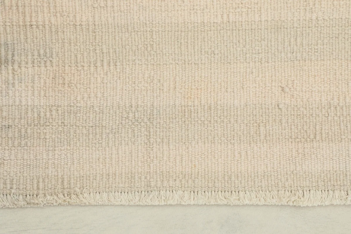Close-up detail of the hand-knotted wool pile and subtle texture of the ivory and cream rug.