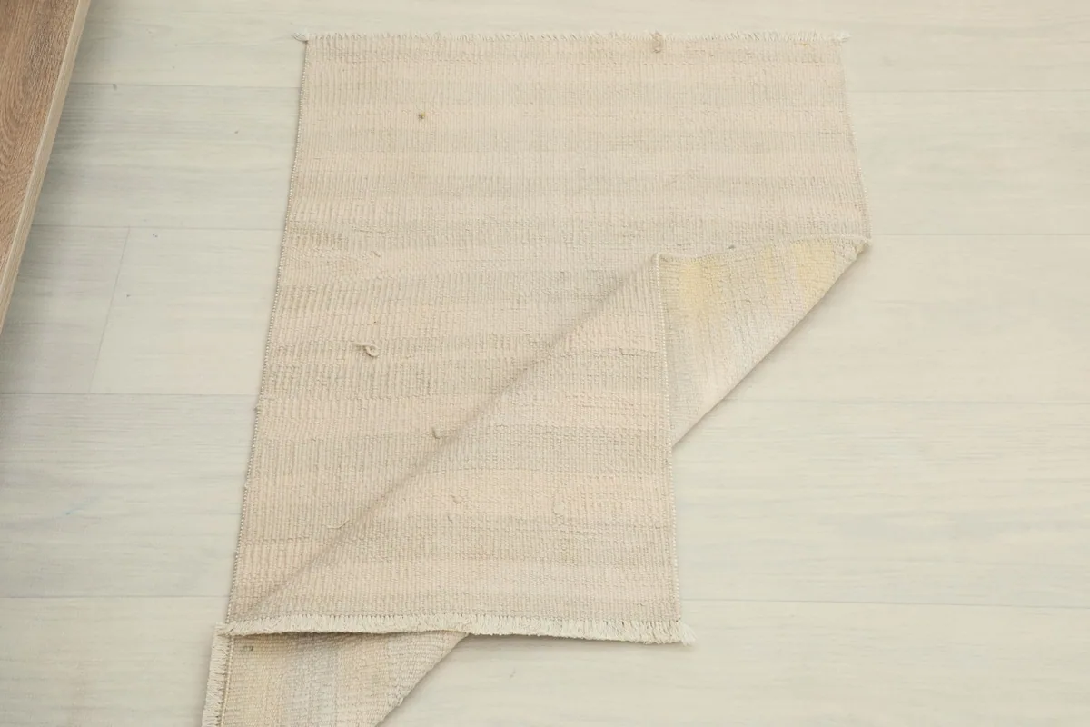The ivory and cream rug partially folded, showing its flexibility and full dimensions.
