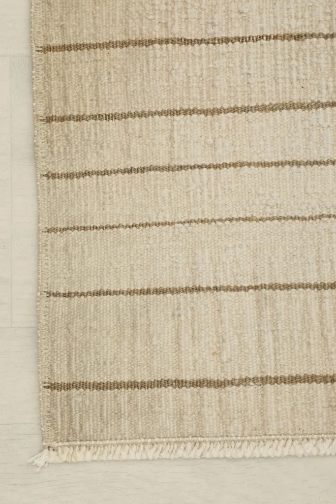 Edge view of the doormat, showing the simple finishing and the striped pattern extending to the side.