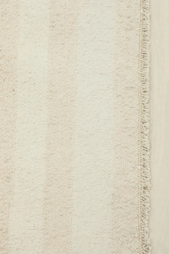 Close-up detail of the cream and beige stripes and the hand-knotted texture of the rug's pile.