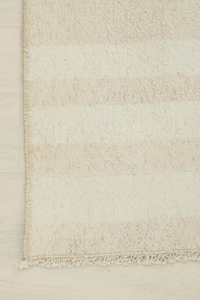 Corner detail of the rug, showcasing the finished edge and a hint of the fringe.