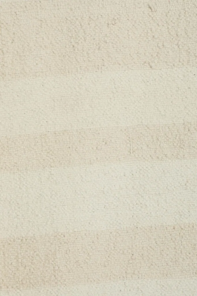 Detailed view of the low wool pile, showing the variation in cream and beige tones within the stripes.