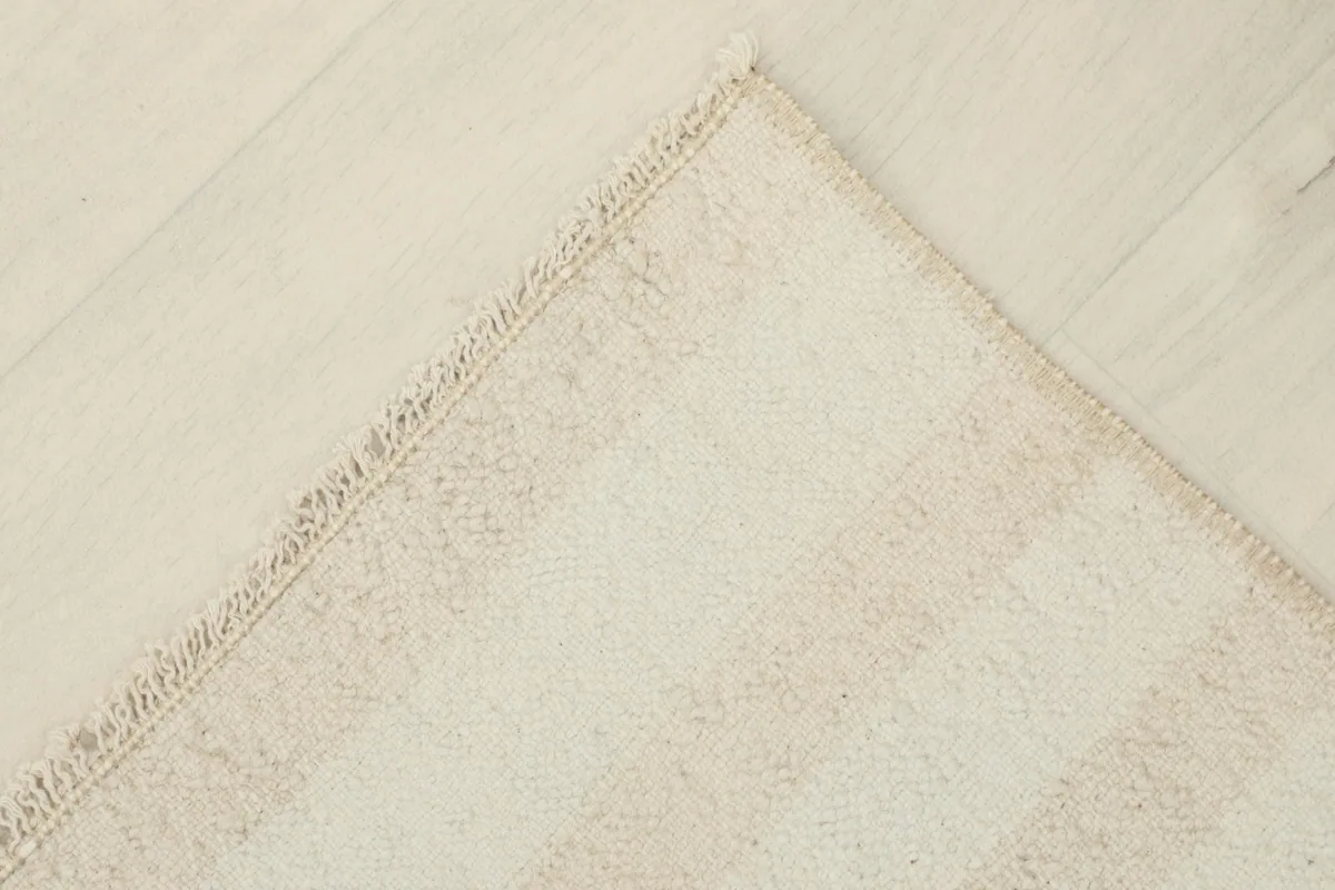 View of the underside of a corner of the rug, revealing the cotton foundation and hand-knotted construction.