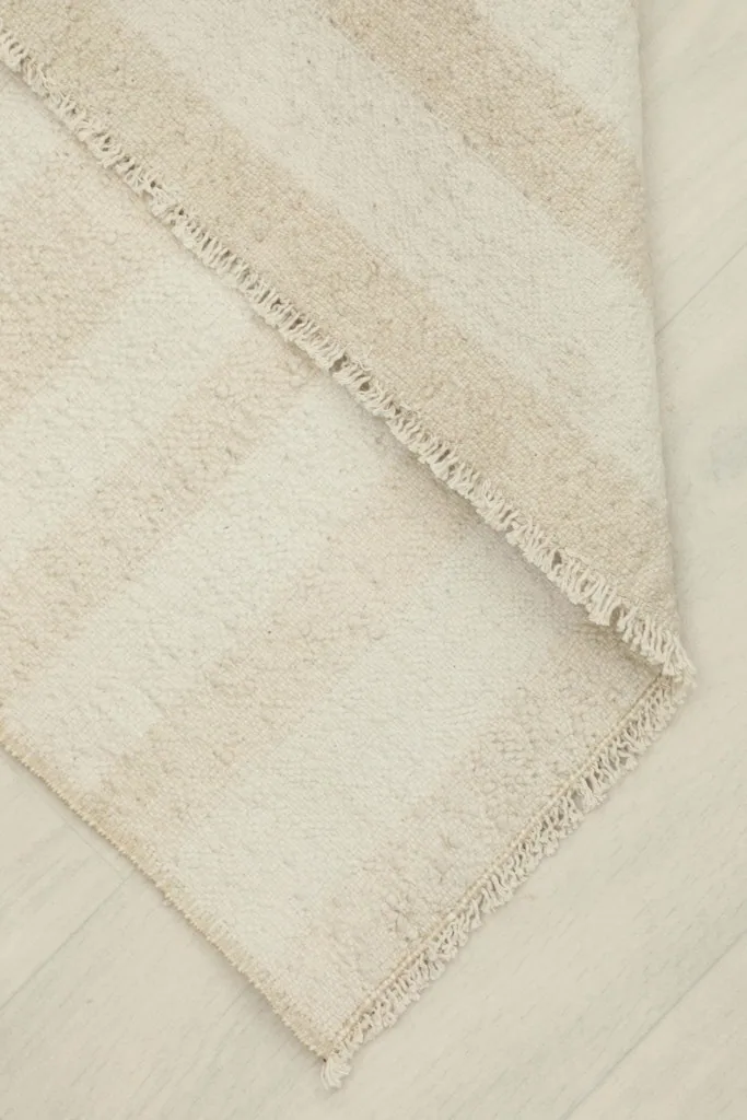 Close-up of the rug folded back, showing the thickness and flexibility of the vintage wool pile.