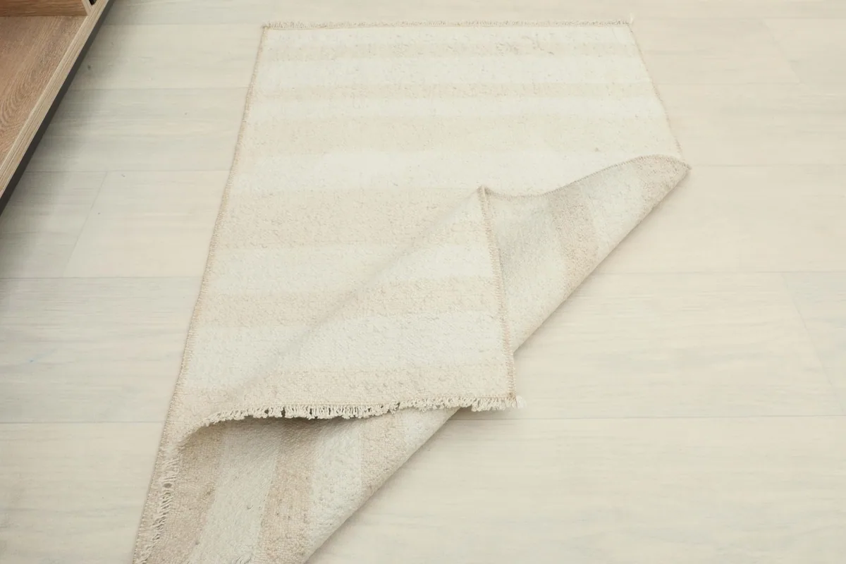 The rug partially folded, illustrating its soft drape and the subtle variations in its striped pattern.