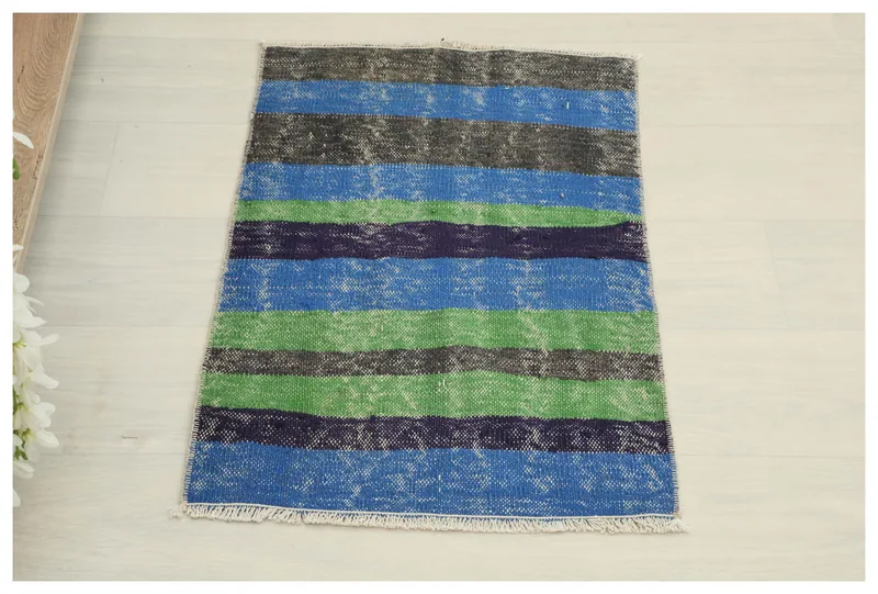 Full overhead view of the blue, green, navy, and gray striped vintage Anatolian rug on a white background.