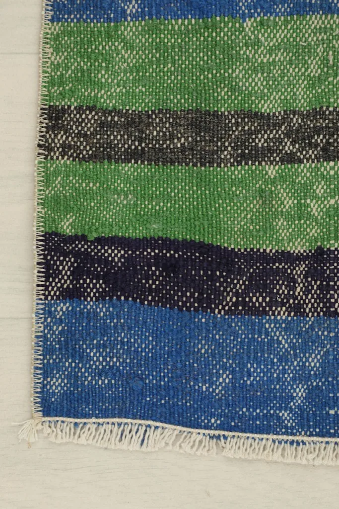 Another corner detail, focusing on the green and gray stripes and the rug's edge.