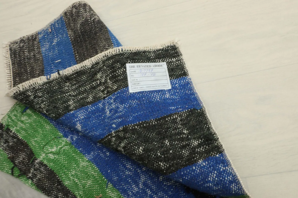 View of the back of the rug, revealing the hand-knotted construction and care label.