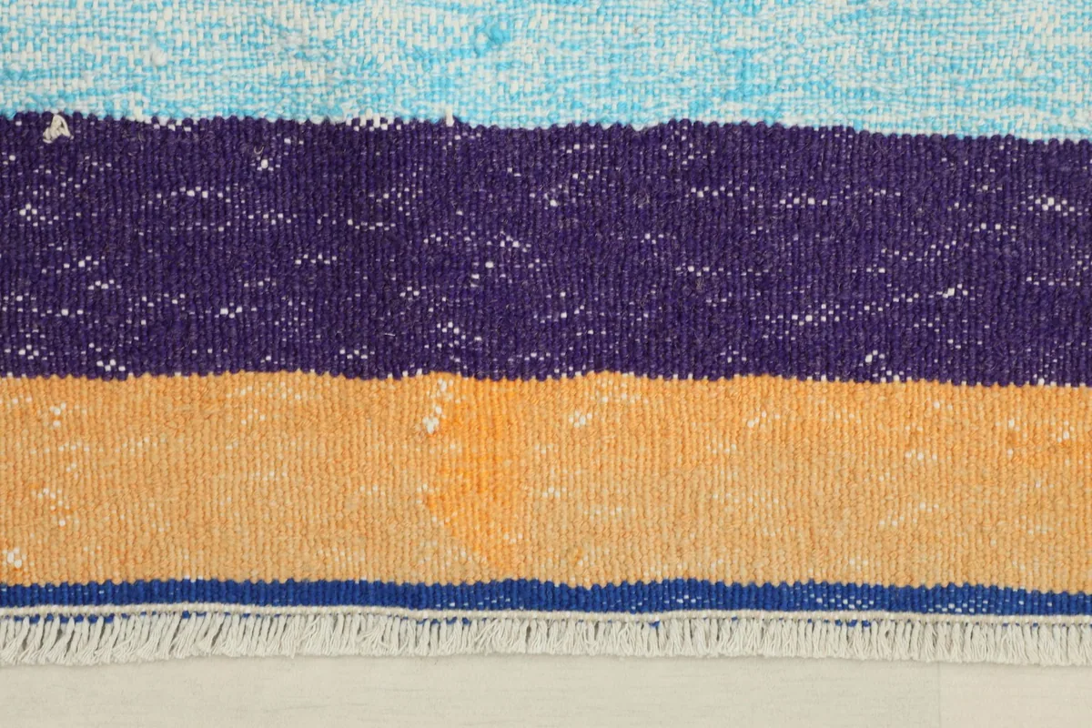 Close-up detail of the rug's stripes and fringe, highlighting the hand-knotted texture.
