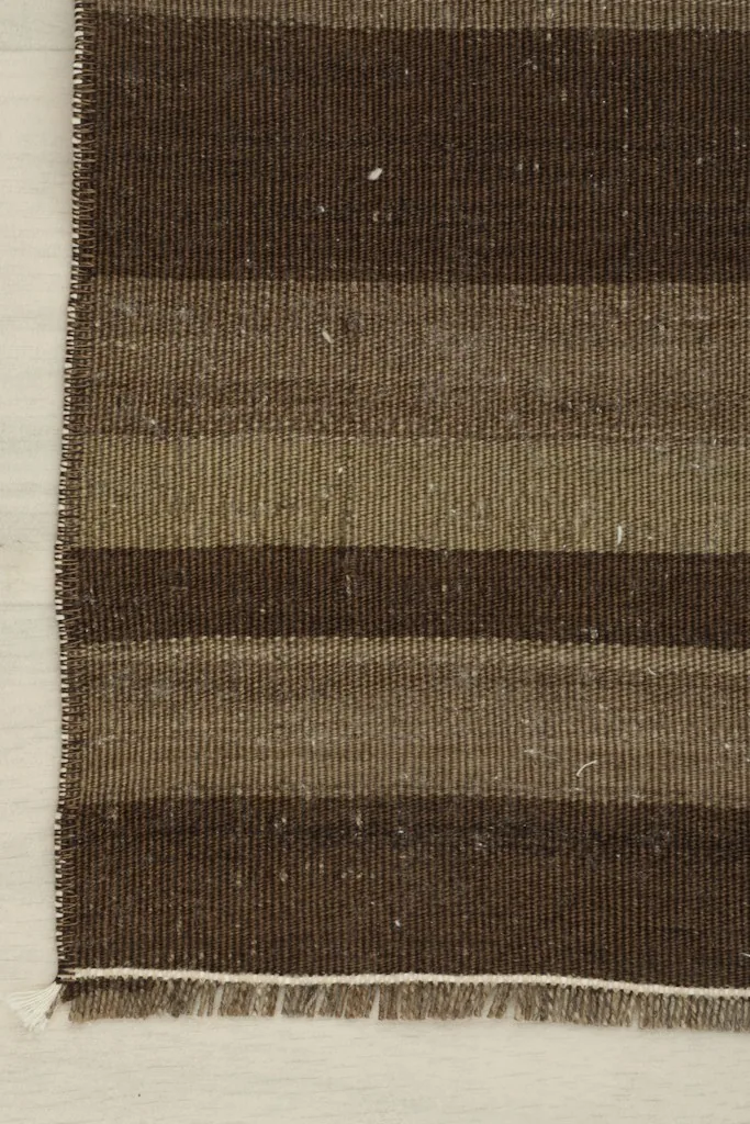 Close-up of the rug's corner, showing the tightly woven edge and short, natural fringe.