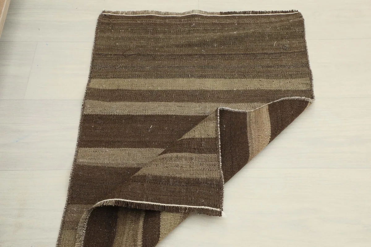 View of the rug with one corner folded back, showing the back of the rug and overall pattern.